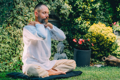 Male therapist performing reiki therapy self-treatment holding hands over his shoulders. 