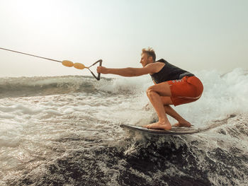 Full length of man surfing in sea against sky