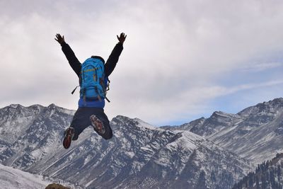 Low angle view of man jumping against mountain