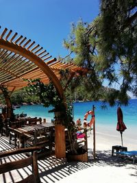 Chairs and tables by swimming pool against clear sky