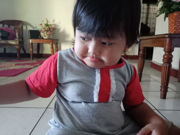 Portrait of cute boy sitting on chair at home