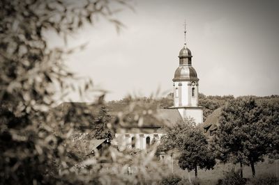 Tower amidst trees and buildings against sky