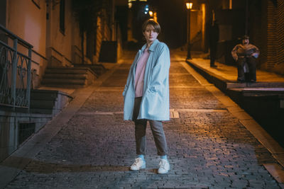 Portrait of woman standing against building at night