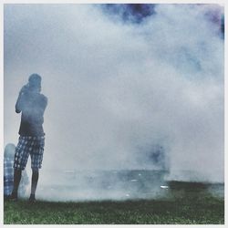 Rear view of man walking on field against sky