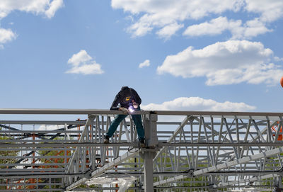 Rear view of woman standing on bridge against sky