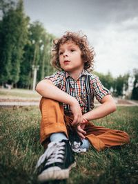 Boy looking away while sitting on field