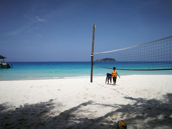 Rear view of girl with brother at beach