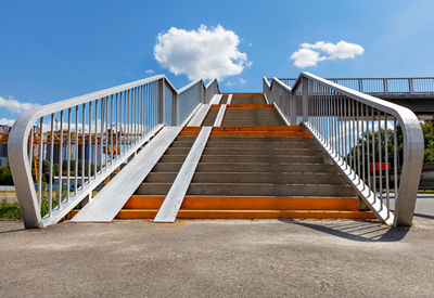 Pedestrian crossing stairs over the highway against the background of the blue sky and white clouds.