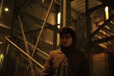 Young man in hoodie standing outdoors at night