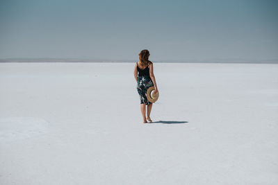 Rear view of woman walking on sand