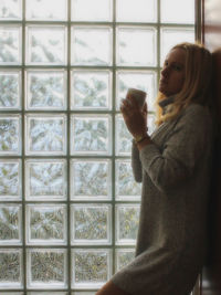 Side view of woman holding glass window