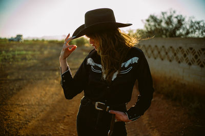 Side view of a woman in cowboy hat and western shirt at golden hour