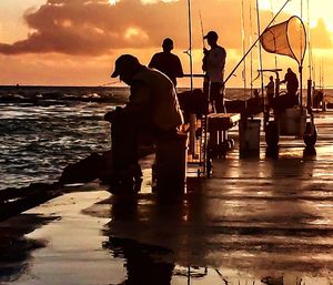 Silhouette of people on pier at sunset