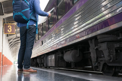 Low section of man standing at railroad station platform