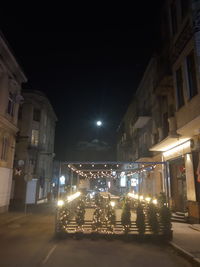 Illuminated street amidst buildings in city at night