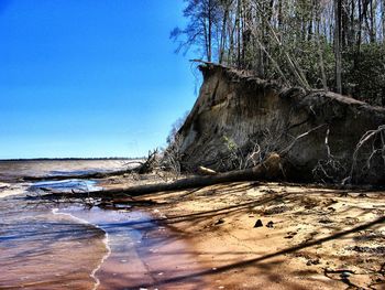 Surface level of beach against clear blue sky