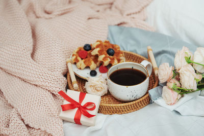 Romantic breakfast with coffee, waffles, gift box and rose flowers.