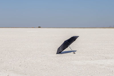 Black umbrella on landscape against clear blue sky during sunny day