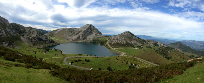 Aerial view of lake enol by mountains against cloudy sky