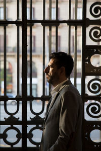 Businessman looking away while standing by gate