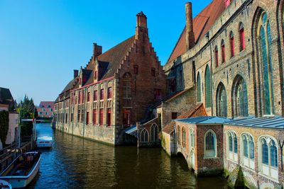 Brugge canal amidst buildings against clear sky in city