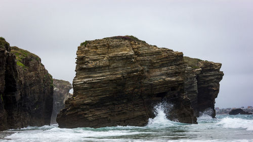 Rock formation by sea against sky