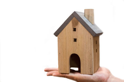 Close-up of hand holding small building against white background