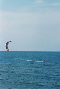 Man kiteboarding in sea against sky