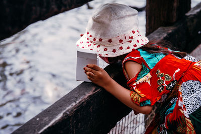 Fancy little girl wearing hat at the lake. view from behind.