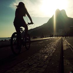 Man cycling on road against sky