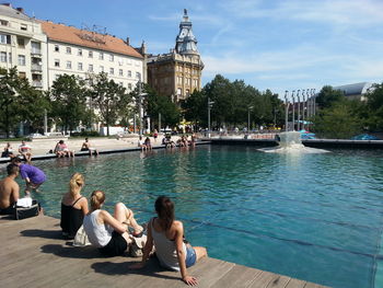 People relaxing by poolside in city