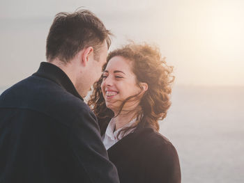 Young couple romancing while standing by sea against sky