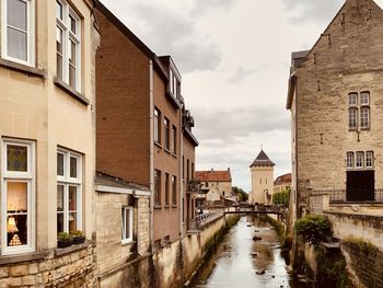 Canal amidst buildings in city against sky