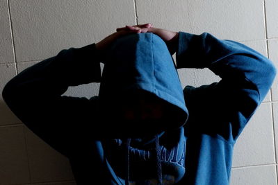 Rear view of man sitting against wall at home