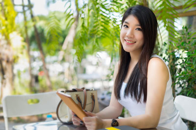 Portrait of young woman using digital tablet while sitting at table