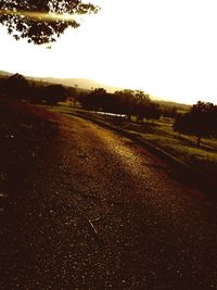 Road amidst field against clear sky