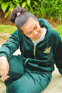 Full length of a smiling young woman sitting on plant