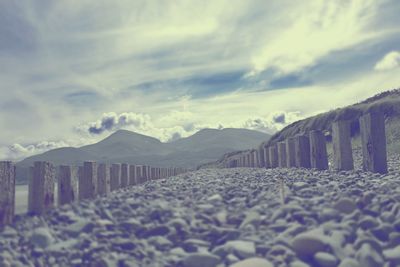 Surface level view of pebbles at beach against cloudy sky at murlough bay