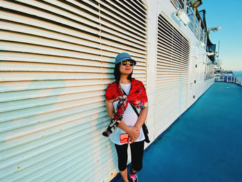 Full length of young woman standing against building