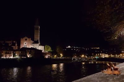 River by illuminated city against clear sky at night