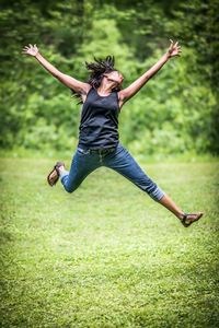 Full length of woman jumping on field against plants