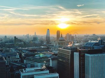 Aerial view of buildings in city against sky during sunset