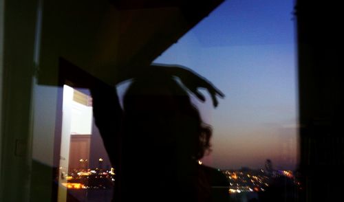 Portrait of silhouette man against illuminated city at night