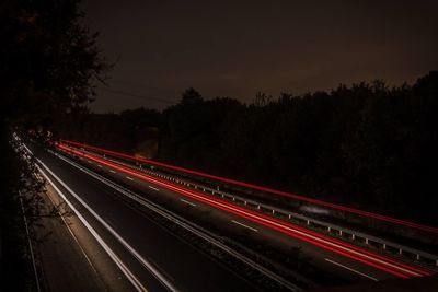 Light trails on road against sky at night