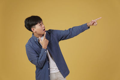 Boy standing against yellow wall