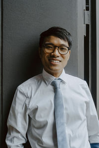 Portrait of smiling businessman against wall