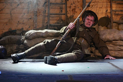 Full length of army soldier sitting on street by stacked sacks