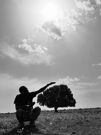 Man sitting on land against sky