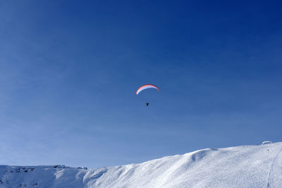 Low angle view of person paragliding against sky