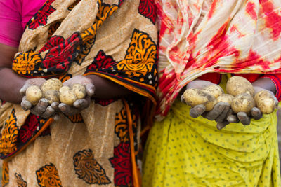 Midsection of women holding potatoes